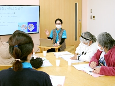 介護施設での健康講座。スタッフが高齢者向けに医療・保健情報についてのセミナーを実施中。